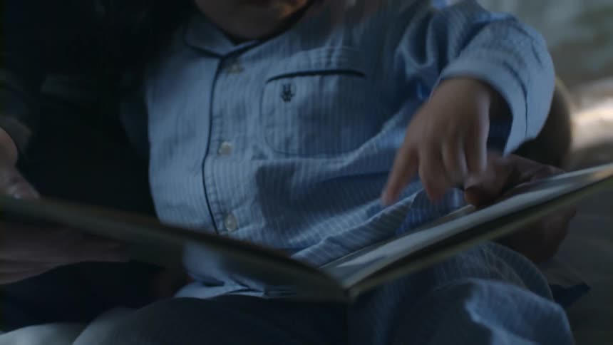A child is reading a book with her father