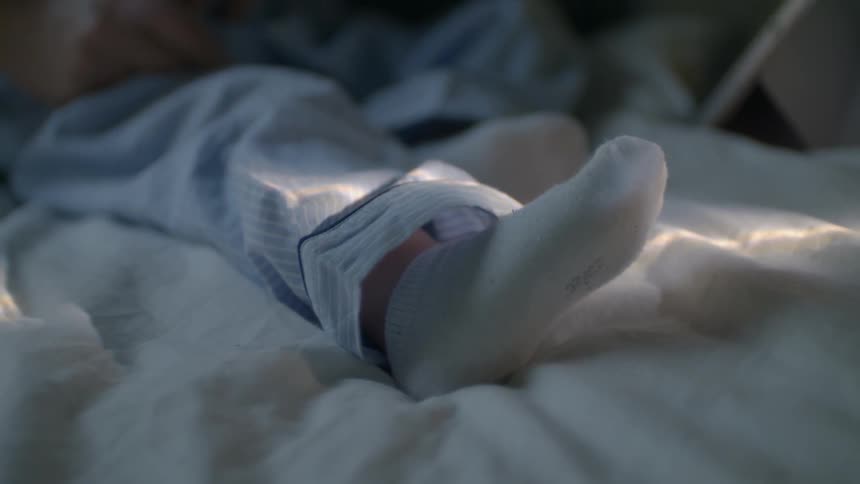 A child's feet in socks and pajamas on a bed