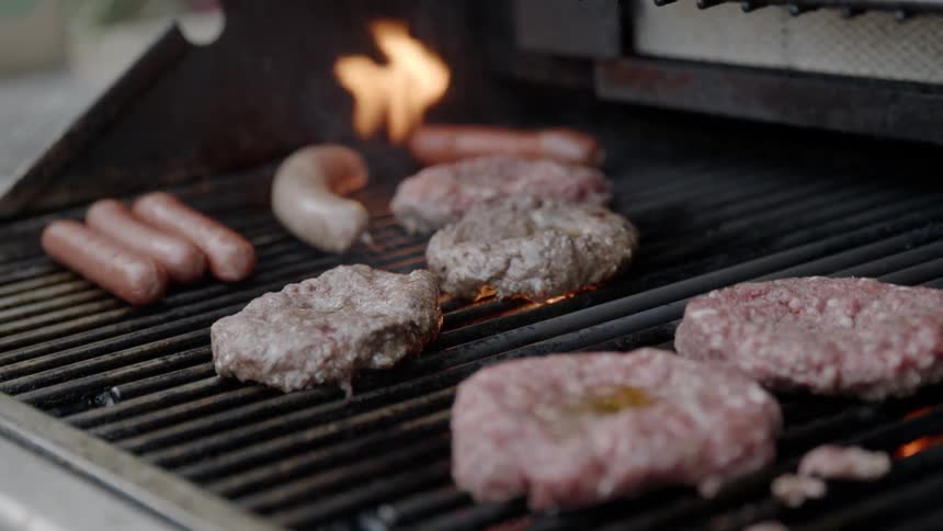 Burgers and hot dogs being cooked on a grill