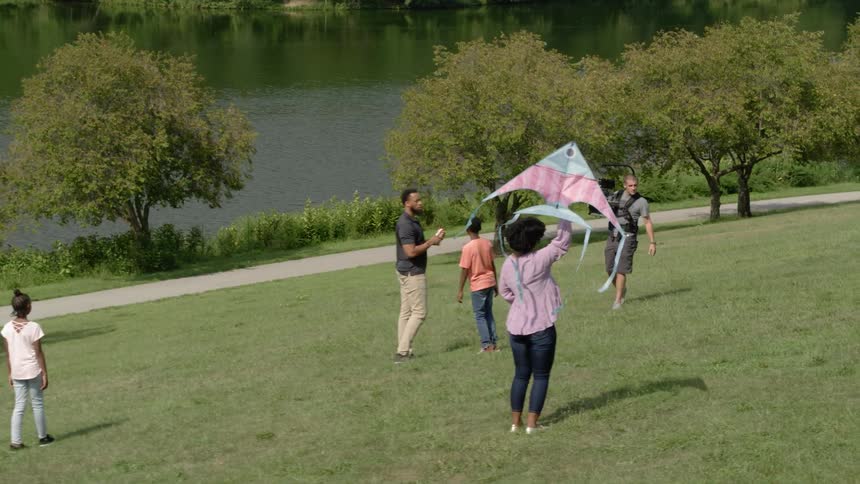 Woman flies a kite in public garden on a sunny day