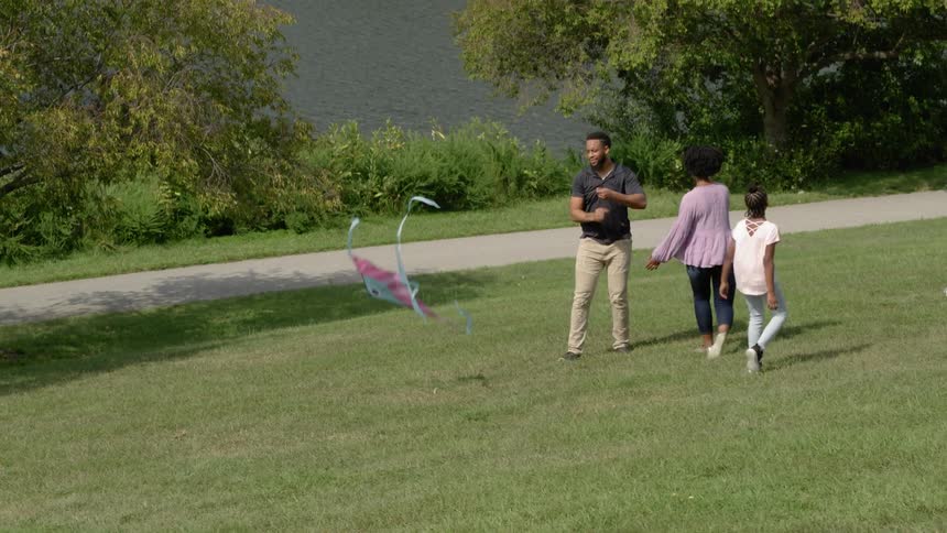 A man walks along with a kite while he waits for his family to join him