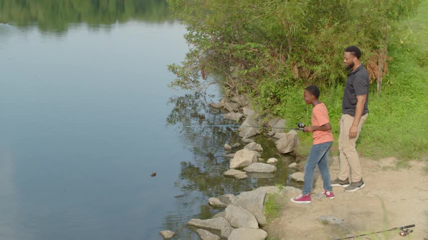 Father and son are fishing by a river