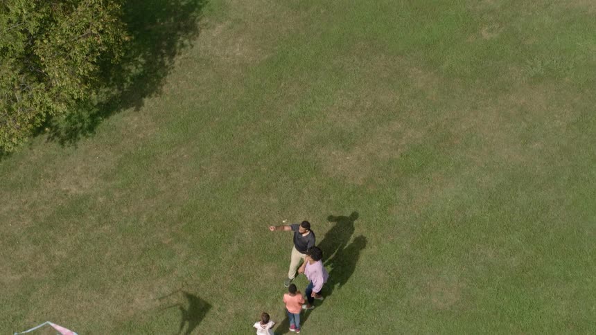A family flies a kite in a grass field