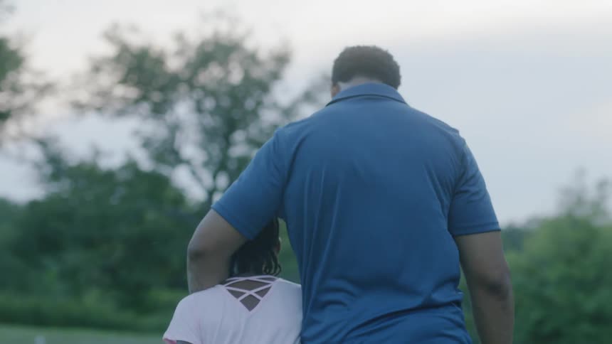 A girl walking in a park with her father
