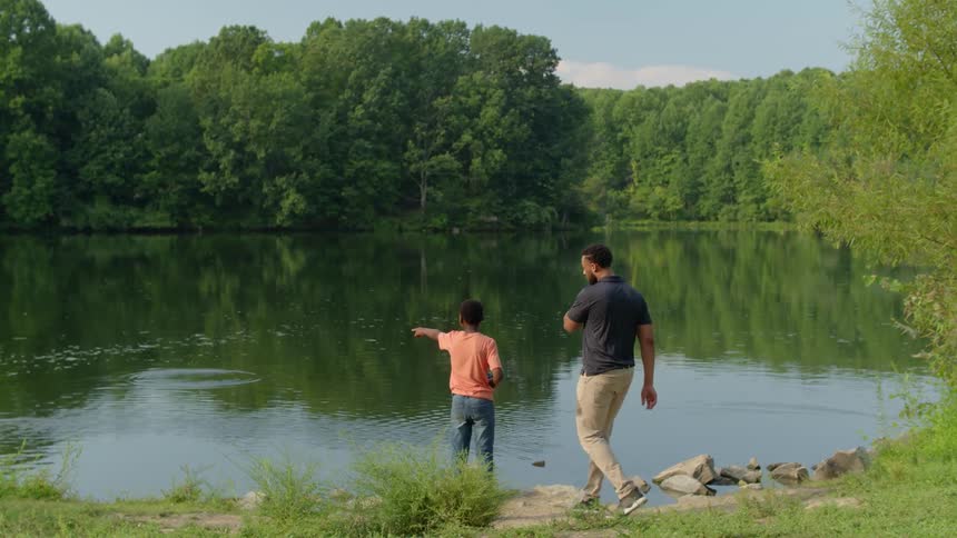 A father and son fishing in a river at a park