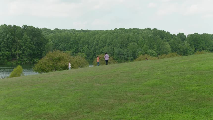 Two children and their parents enjoy a summer scene by a river bank