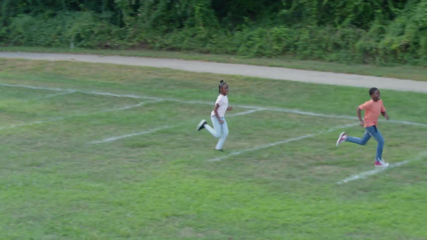 Two kids have a running race while mom and dad watch