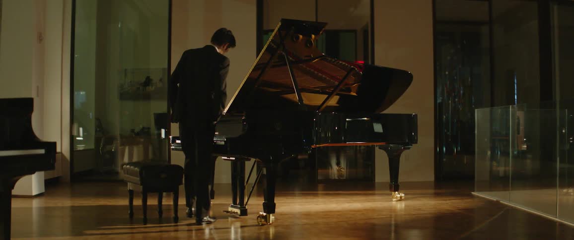 A person is walking towards a piano