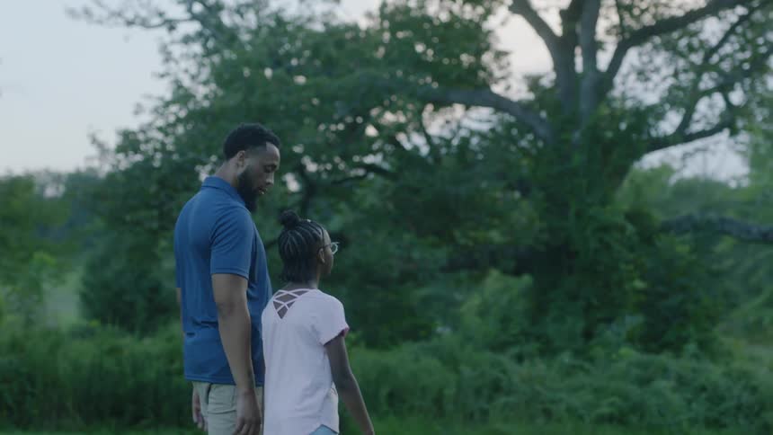 A father and daughter walking in a park