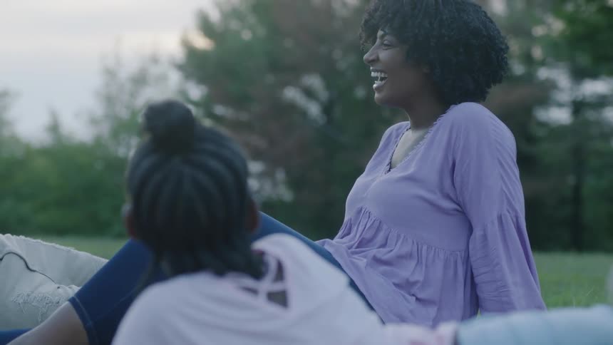 Woman sits on grass with daughter near her