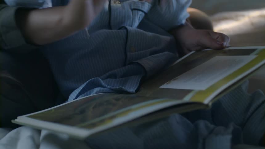 Mother and baby look at a child's book on the couch