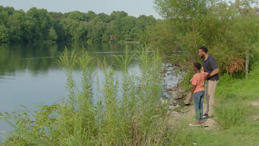Man and boy fish by a lake in the park