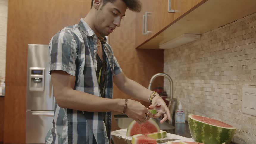 A man puts pieces of watermelon in  a pile