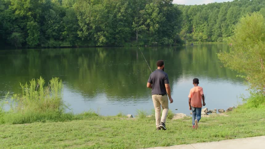A father and son goof around while fishing at a lake