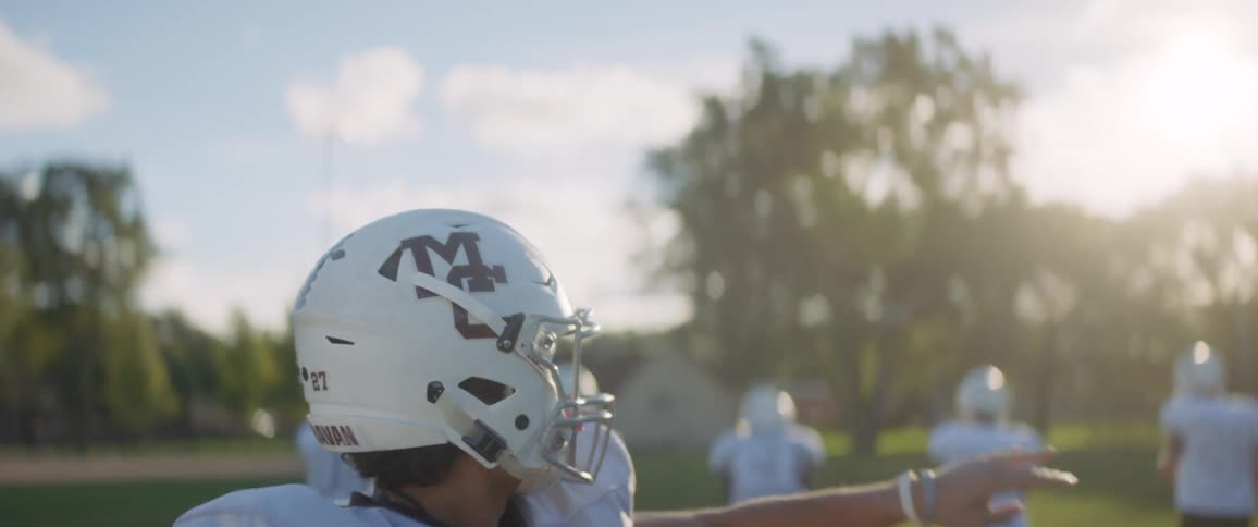A quarterback throws a football while his teammates run away from him
