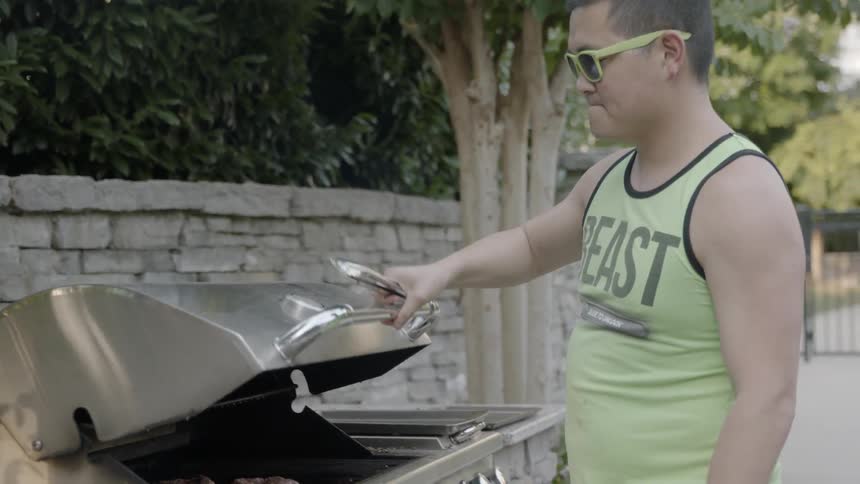 A man cooks on an outdoors grill