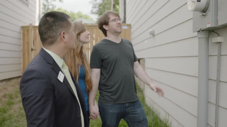 Man shows woman and man watt meter of house