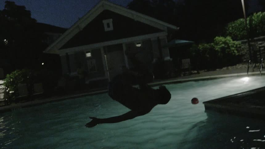 A man runs and jumps into the pool at night