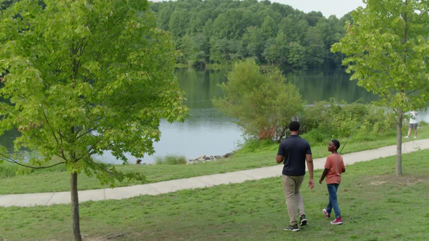Two people walk toward the water with poles
