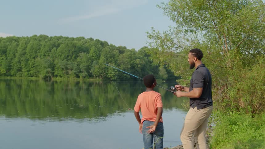 Man and child are fishing by a river