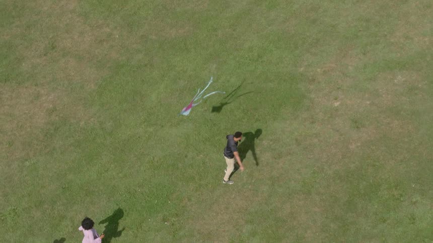 A family play together outside with a kite