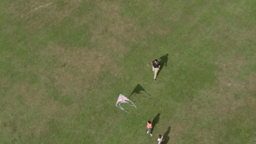 A dad is showing his kids how to fly a kite