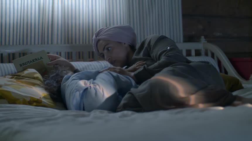 Woman and child are sitting on a bed indoors
