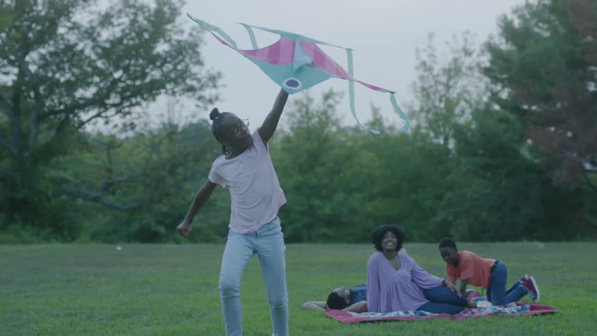 Girl flies a kite happily in park on a sunny day