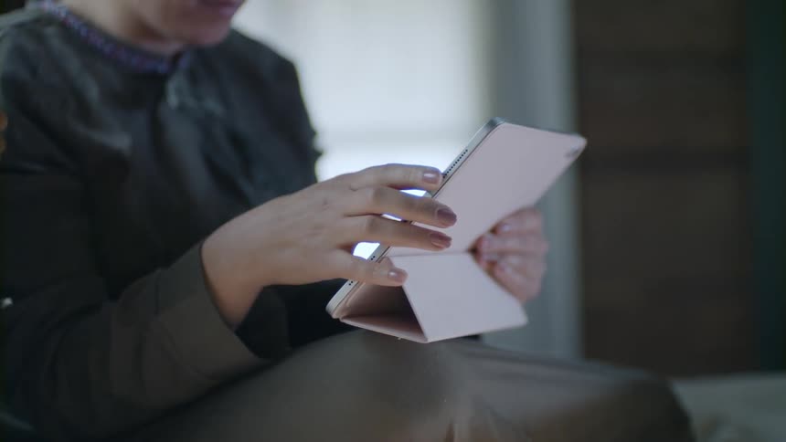 A person sitting and typing on a tablet