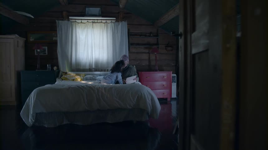 Woman and child are sitting on a bed indoors