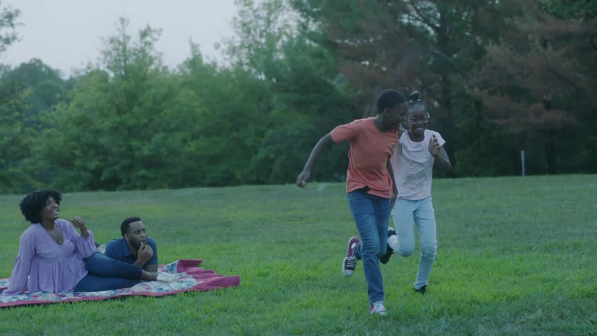 Kids running around next to their parents in a park