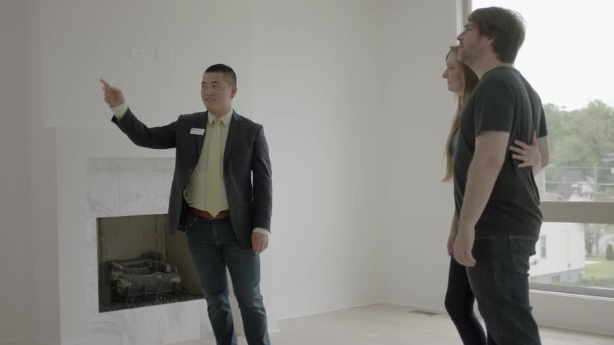 A real estate agent tours a house with a young couple
