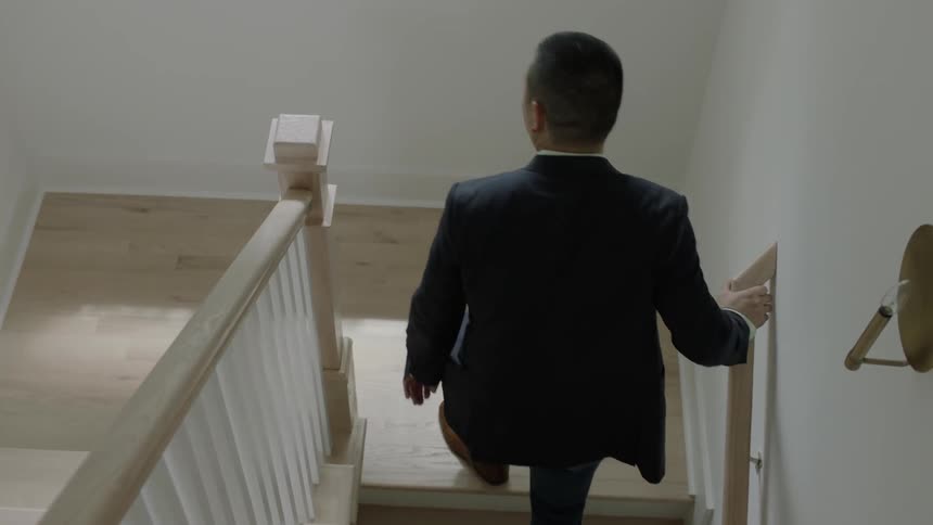 Man holding stair rail goes upstairs with woman
