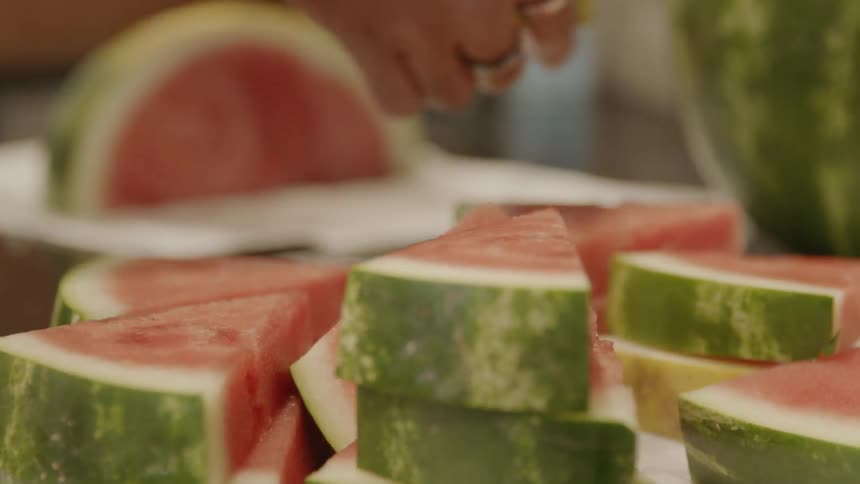 Woman arranging slices of watermelon on table