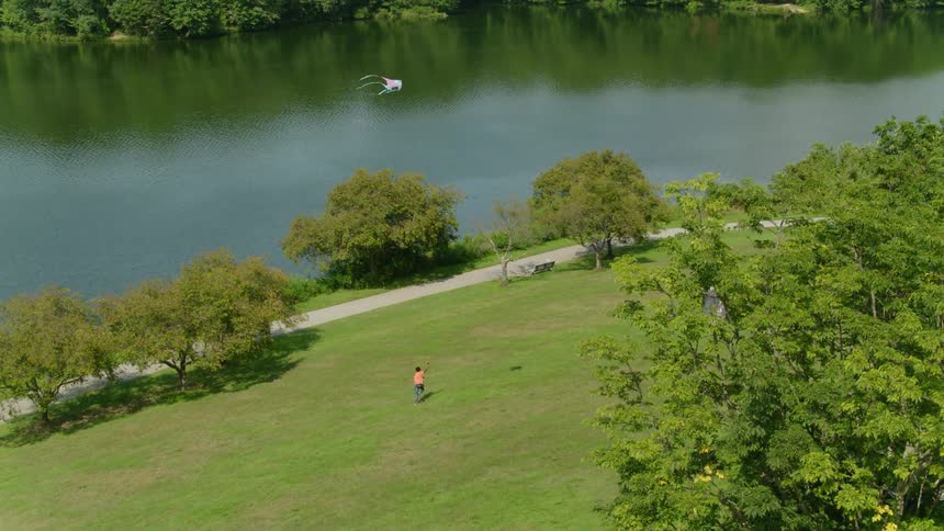 A child is flying a kite by the river