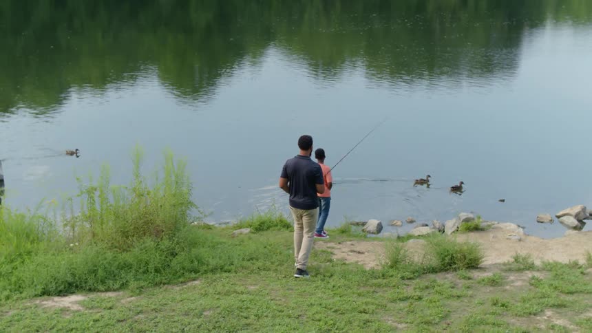 A father and son fish from a lakeshore