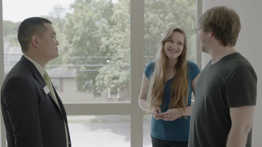 A man talking to a man and woman indoor