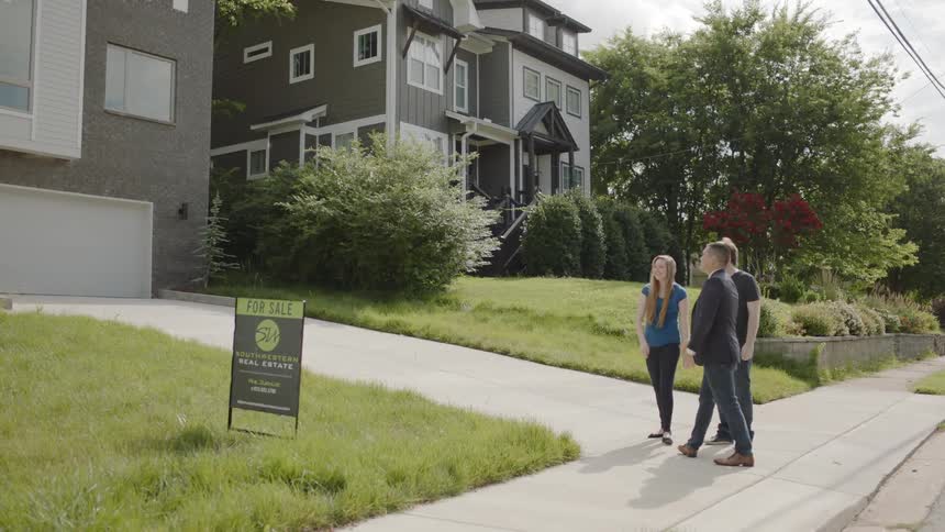 A man greets a couple looking at a house for sale