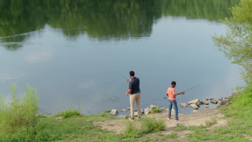 A man and child fish together on a sunny day