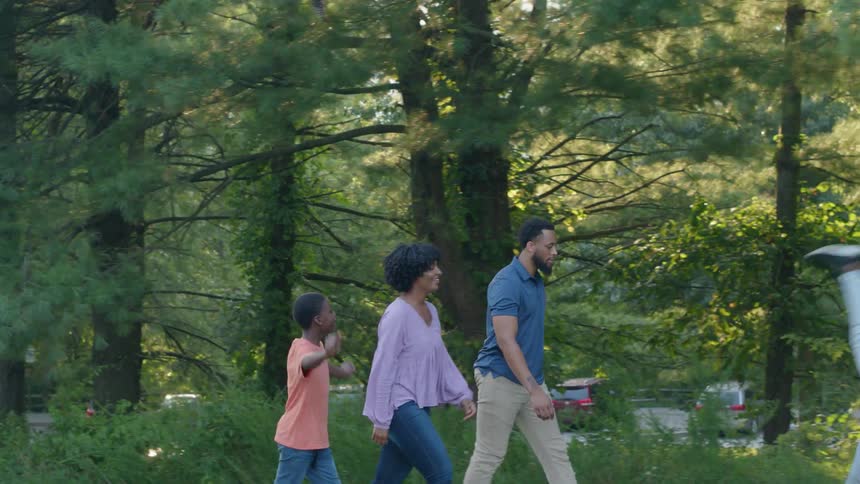 Family walks in park as girl does flips