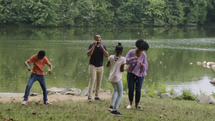 A family playing with soap bubbles next to a river