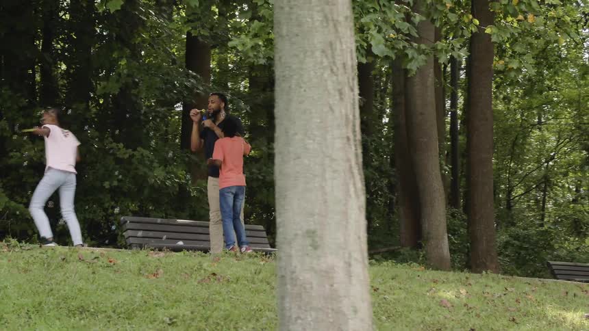 A family blow bubbles outside in nature