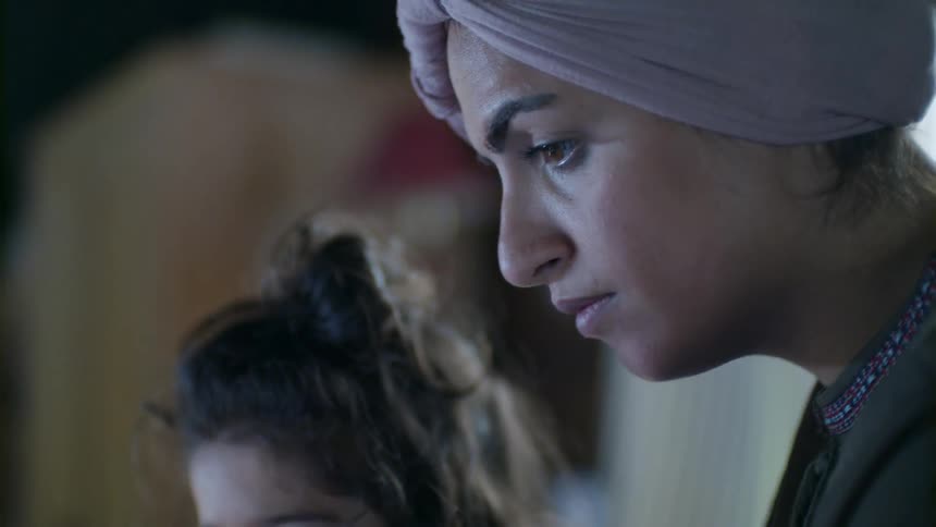A little girl sitting next to and talking to a woman