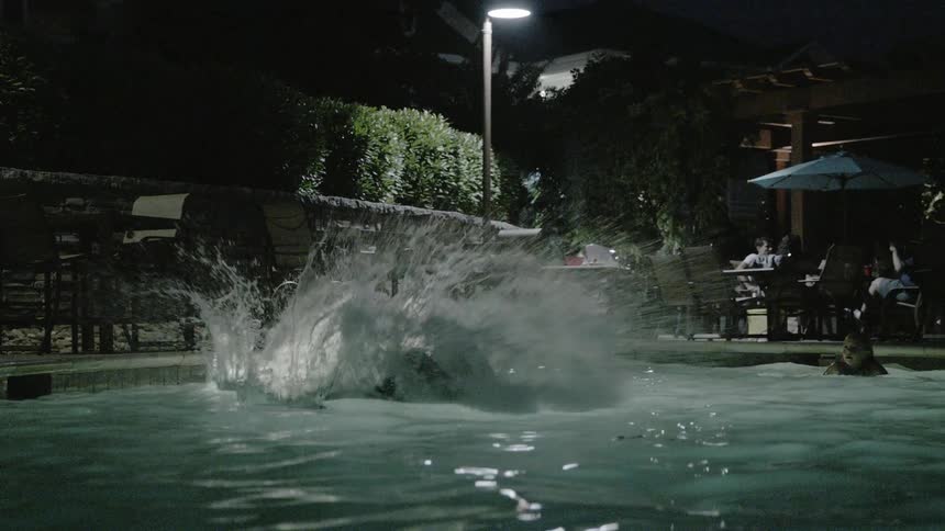 A man jumping in a pool at night