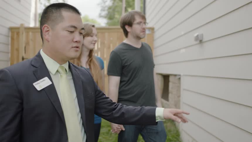 A real estate agent shows a house to a young couple