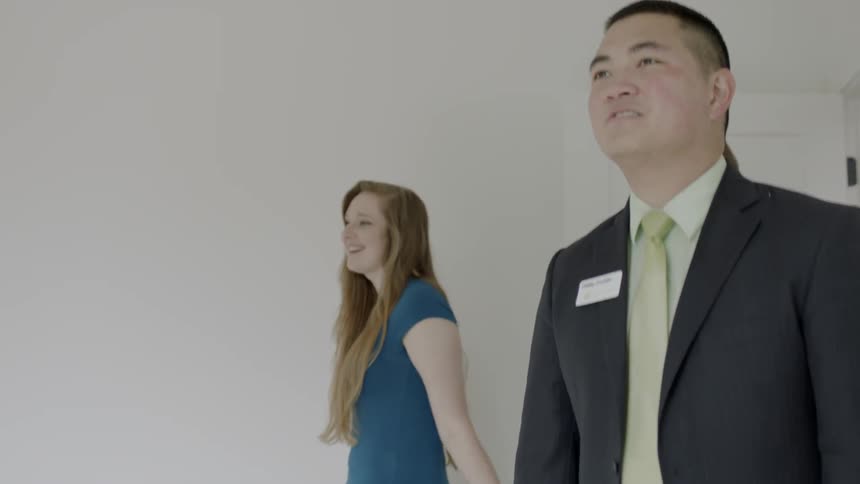 A realtor and couple walk through a door of a home and look around the room