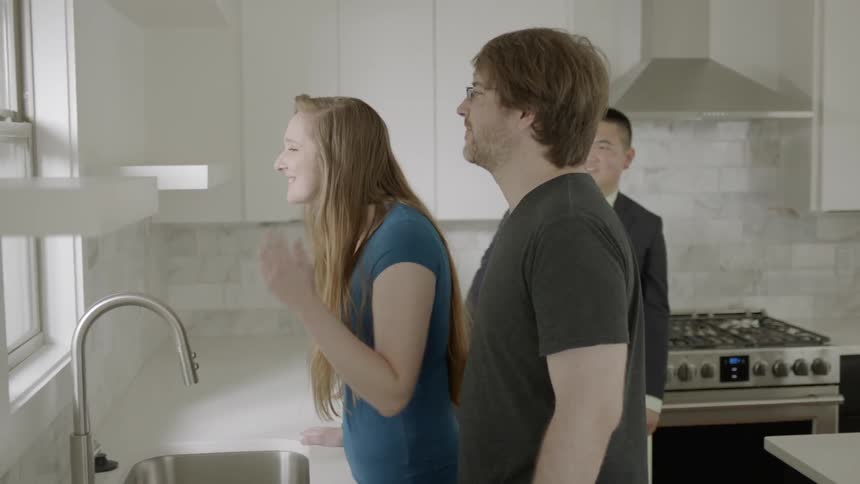 A woman examining a kitchen with a man and an agent