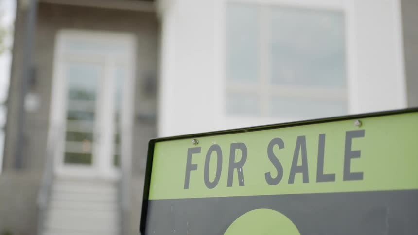 A house with a for sale sign on the front yard