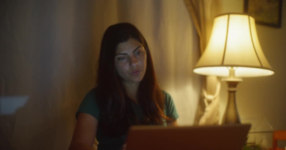 Woman sits in front of computer in the lamp lit  room