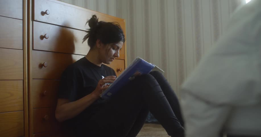 A woman is reading a book while sitting down in a room